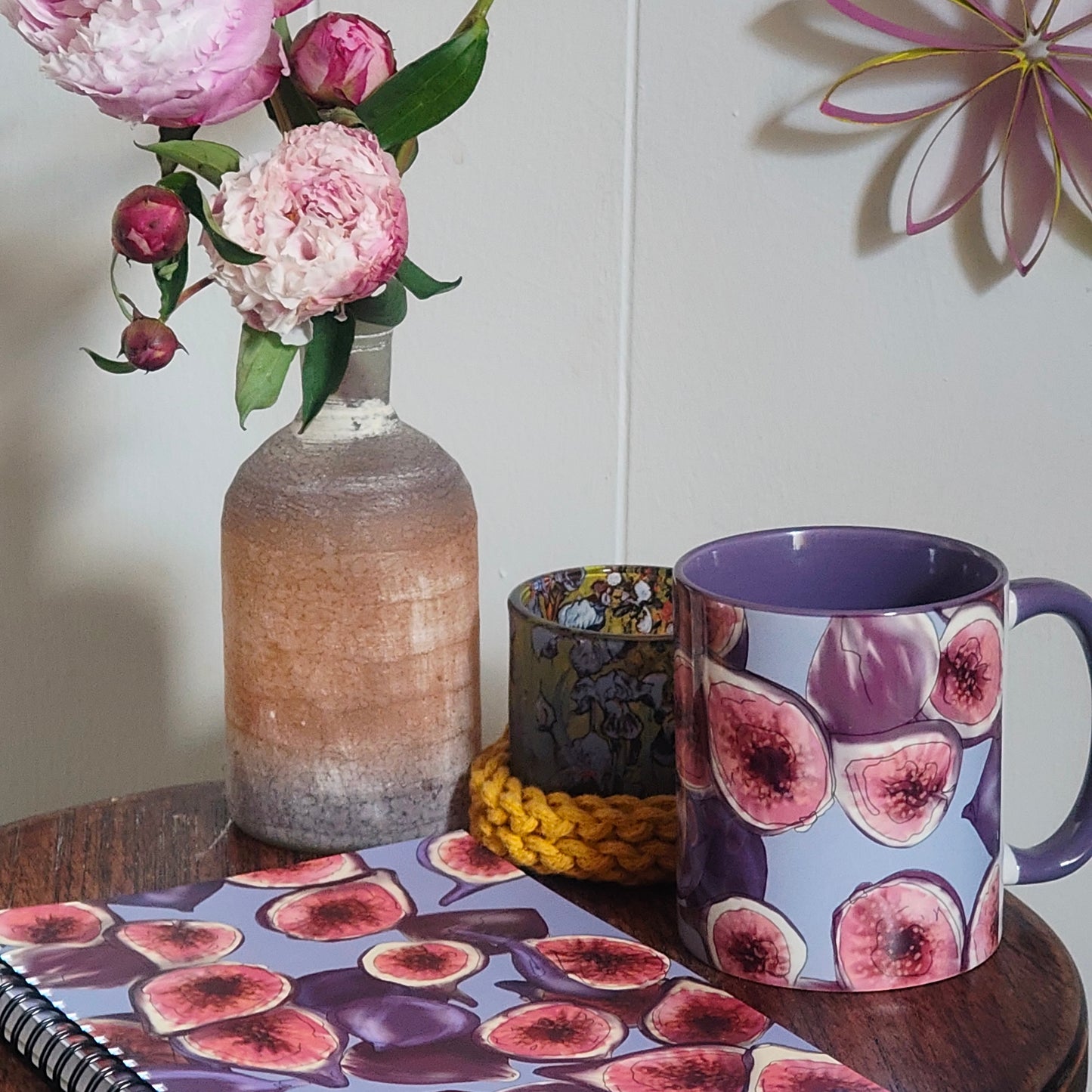 Mug with fig design, notebook, vase with flowers on a wooden surface