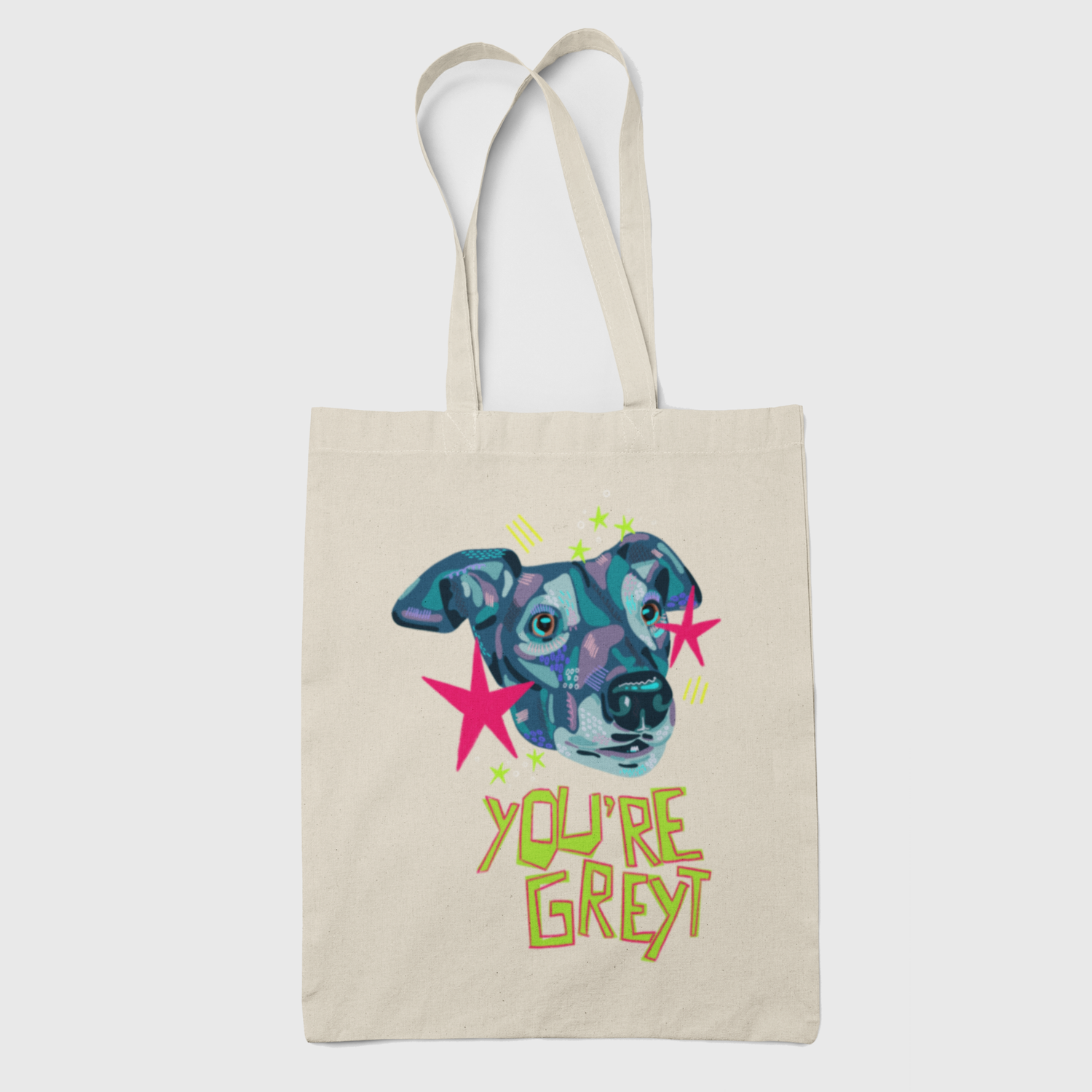A beige canvas tote bag with a colorful graphic of a greyhound's face in blue, purple, and pink, surrounded by pink stars and the text 'YOU'RE GREY' in yellow-green lettering, shown against a light gray background.