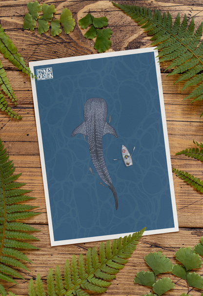 An art print featuring a whale shark and a small boat on a blue water background, styled flat-lay on a rustic wooden surface with green fern leaves around it. The print has a white border and a small 'DYNES DESIGN' logo in the top-left corner.